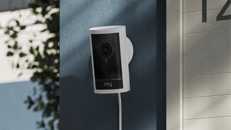 Eine Ring Outdoor Camera Plus an einer blauen Wand in der Nähe eines Hausnummernschilds montiert.