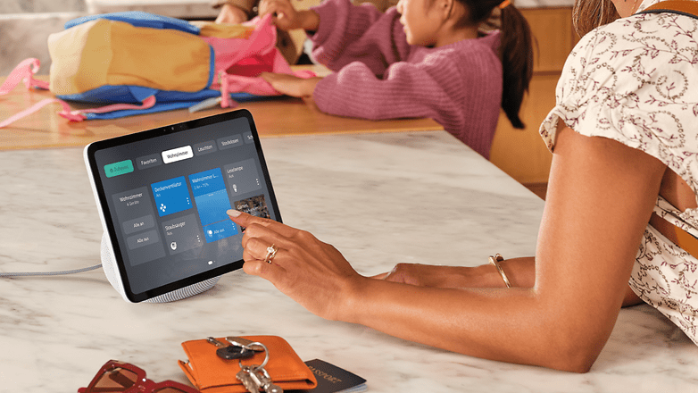 Eine Person nutzt ein Amazon Echo Show 11 auf einer Küchenarbeitsplatte mit Taschen im Hintergrund.