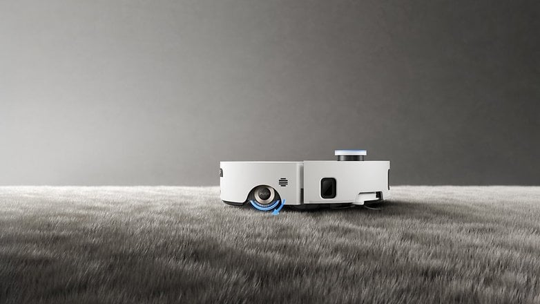 A white robotic vacuum cleaner, the Dreame Aqua10 Roller Complete, on a soft, textured surface. A white robotic vacuum cleaner, the Dreame Aqua10 Roller Complete, on a soft, textured surface.