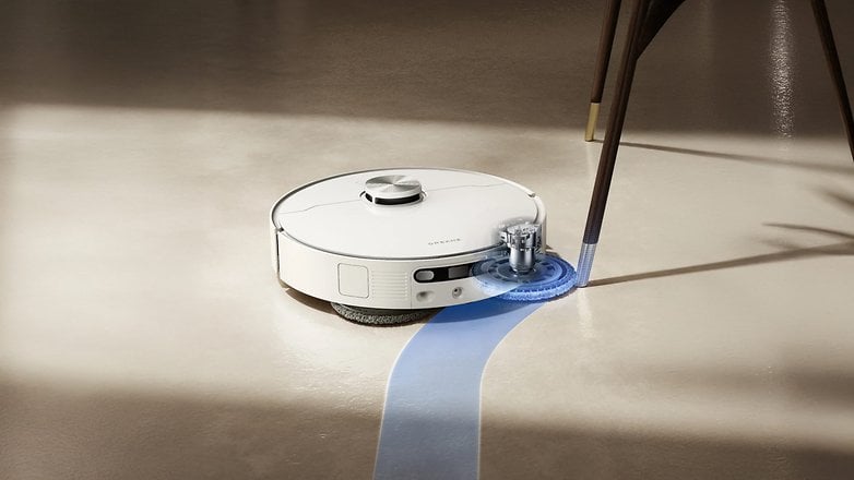 A Dreame L40 Ultra AE robotic vacuum cleaner mopping a floor under a table. A Dreame L40 Ultra AE robotic vacuum cleaner mopping a floor under a table.