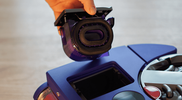 Une main tenant un filtre au-dessus de l'aspirateur Dyson 360 Vis Nav.