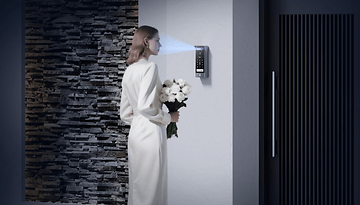 Eine Frau in einem weißen Kleid steht neben dem EZVIZ HP7 Pro-Gerät und hält einen Blumenstrauß.