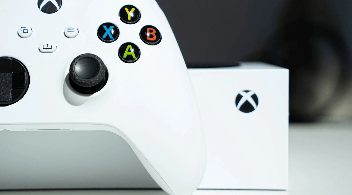 Un contrôleur Xbox blanc avec des boutons colorés à côté d'une boîte Xbox.