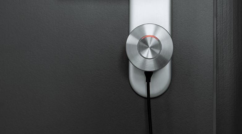 Close-up of a Nuki Smart Lock Ultra mounted on a door with a black cable attached.