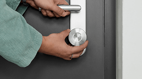 A person is using a Nuki Smart Lock Ultra on a door handle.