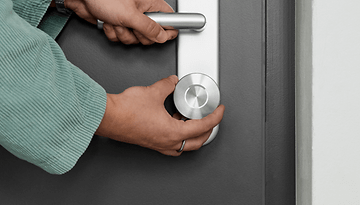 A person is using a Nuki Smart Lock Ultra on a door handle.