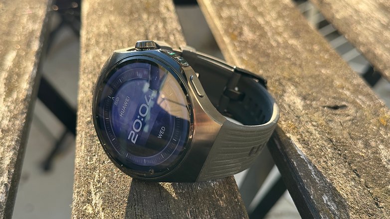 Huawei Watch 5 em uma superfície de madeira mostrando a hora 20:04, com fundo azul e quarta-feira. Huawei Watch 5 em uma superfície de madeira mostrando a hora 20:04, com fundo azul e quarta-feira.