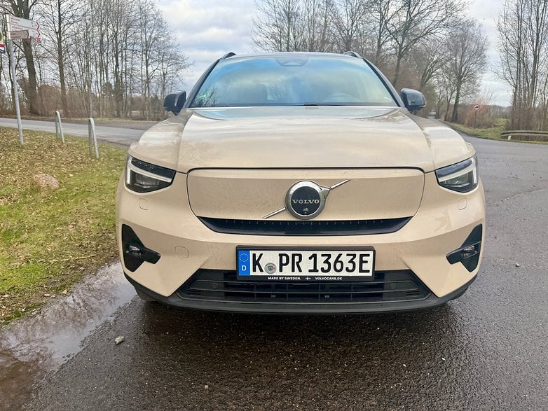 Vue de face d'un SUV Volvo EX40 beige garé sur une route.