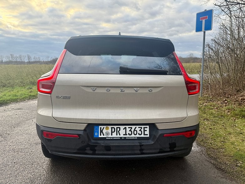 Vue arrière d'une Volvo EX40 garée au bord de la route avec un panneau de sens interdit à proximité.