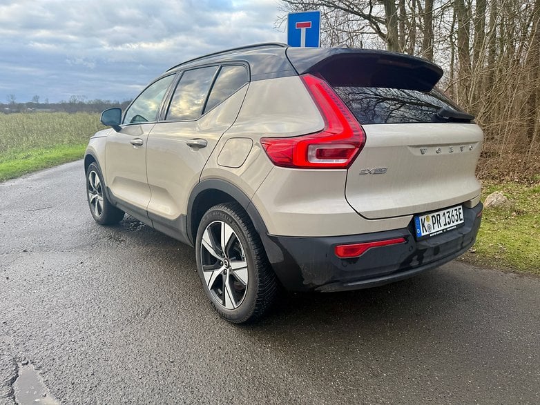 Une Volvo EX40 garée sur une route avec un panneau de signalisation en arrière-plan et des arbres tout autour.