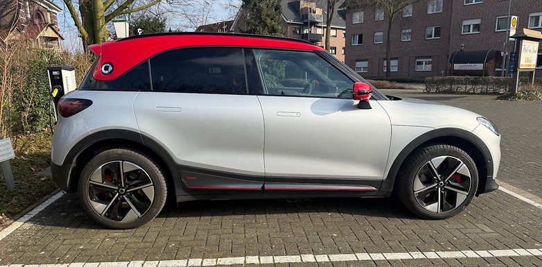 Une voiture Smart #1 Brabus garée, avec un design élégant, toit rouge et roues sportives.