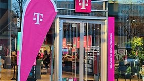 Eine Flagge mit dem Logo der Telekom steht vor einem Telekom-Shop