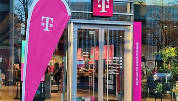 Eine Flagge mit dem Logo der Telekom steht vor einem Telekom-Shop