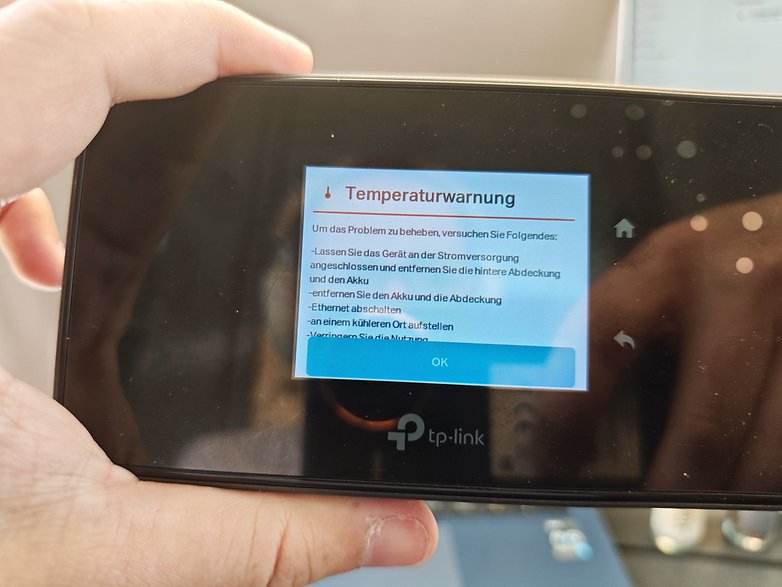 Ein TP-Link M8550-Gerät zeigt eine Temperaturwarnmeldung mit Problemlöseschritten an. Ein TP-Link M8550-Gerät zeigt eine Temperaturwarnmeldung mit Problemlöseschritten an.