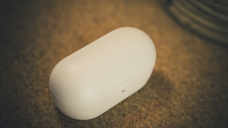 Um estojo branco de fones de ouvido Sony sobre uma superfície de cortiça. Um estojo branco de fones de ouvido Sony sobre uma superfície de cortiça.