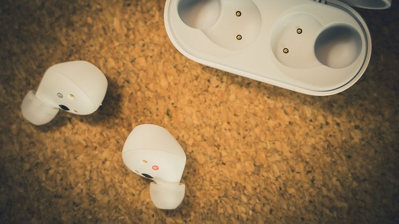 Fones de ouvido sem fio Sony brancos ao lado de seu estojo de carregamento em uma superfície de cortiça. Fones de ouvido sem fio Sony brancos ao lado de seu estojo de carregamento em uma superfície de cortiça.