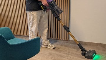 Eine Person benutzt einen Akkusauger in einem modernen Raum.