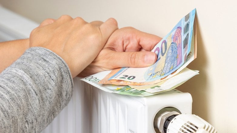 Des mains placent des billets en euros sur un radiateur blanc.