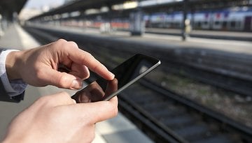 Smartphone in Händen am Bahnhof