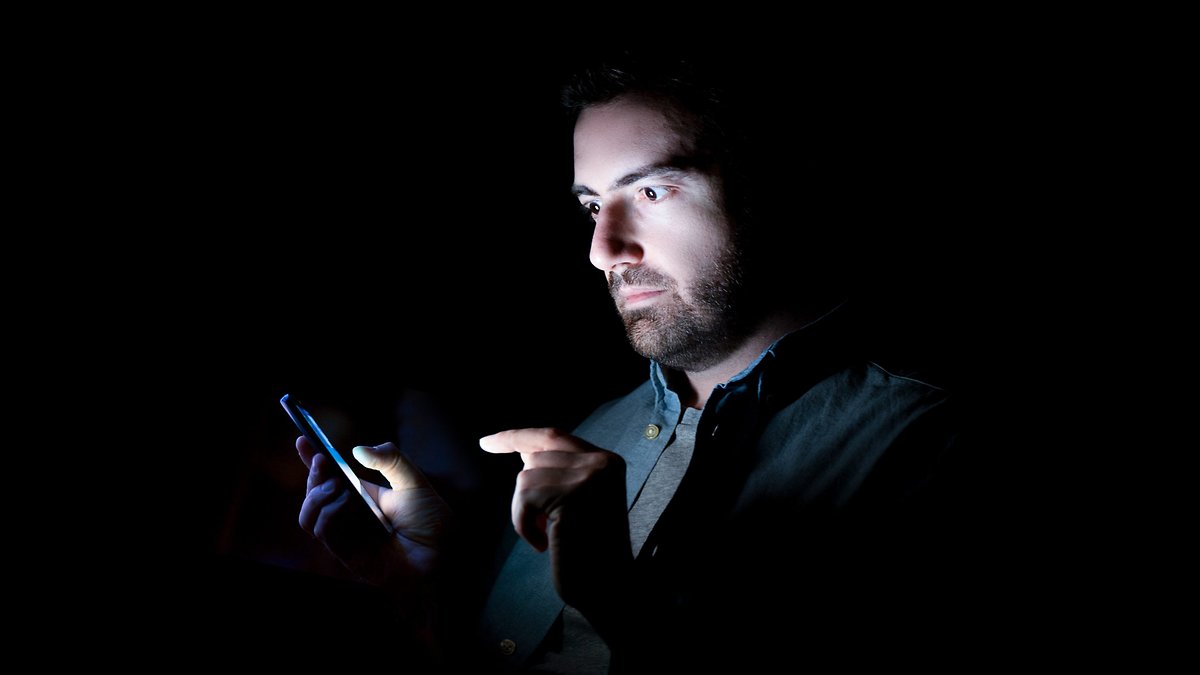 mann mit smartphone im dunkeln