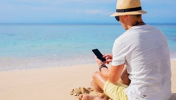 Mann mit Smartphone am Strand