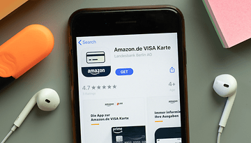 Ein Smartphone zeigt die Amazon.de VISA Karten-App mit einer Bewertung von 4,7 Sternen und Download-Optionen.