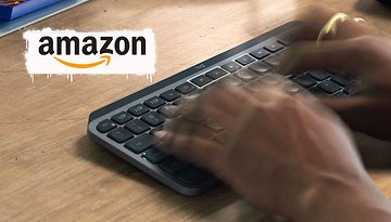 Hände tippen auf einer Logitech MX Keys Mini Tastatur auf einer Holzoberfläche mit einem Amazon-Logo.
