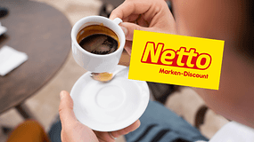 Eine Person hält eine Tasse Kaffee mit einer kleinen Untertasse, mit einem Schild 'Netto Marken-Discount'.