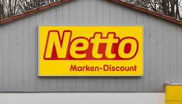 Netto Marken-Discount-Logo auf gelbem Hintergrund an einer grauen Wand angebracht.