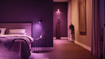 Ein gemütliches Schlafzimmer mit lila Wänden, intelligenter Philips Hue Beleuchtung und einem dekorativen Flur.