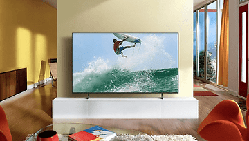 Samsung 4K-TV zeigt einen Surfer, der in einem modernen Wohnzimmer eine Welle reitet.