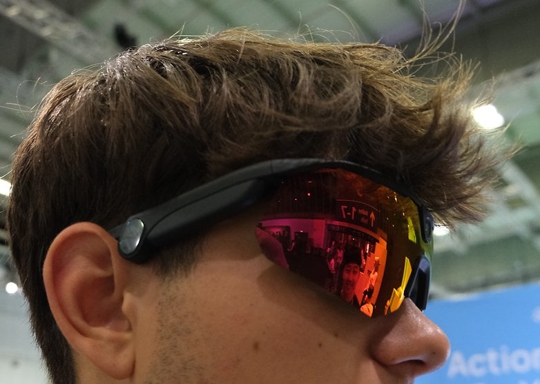 A close-up of a person wearing sunglasses with reflective lenses, showcasing a colorful background.